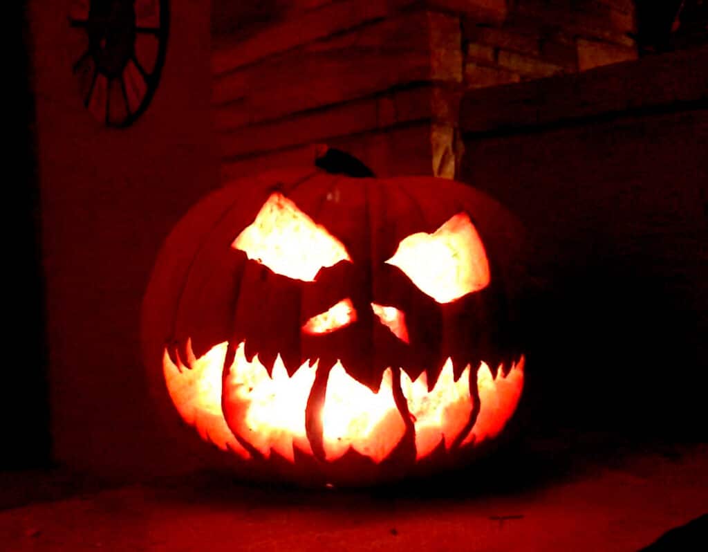 Jack-O-Lantern with lit candle at night on front porch