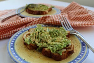 2 spicy avocado toasts on plates with forks