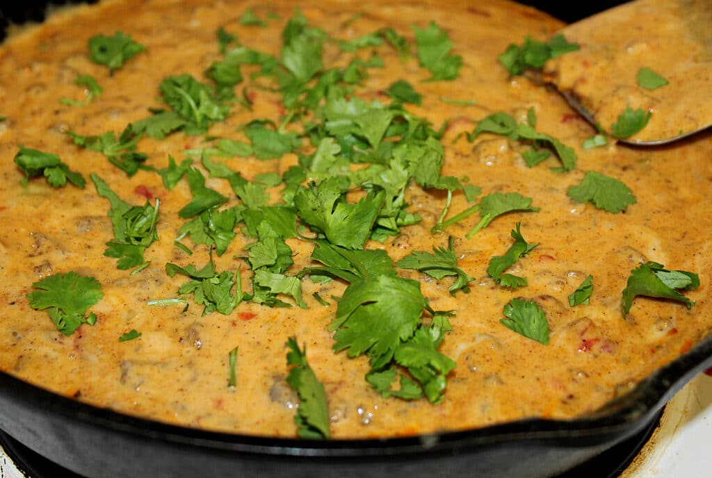 Spicy Rotel Sausage Cheese Dip with cilantro in a cast iron skillet