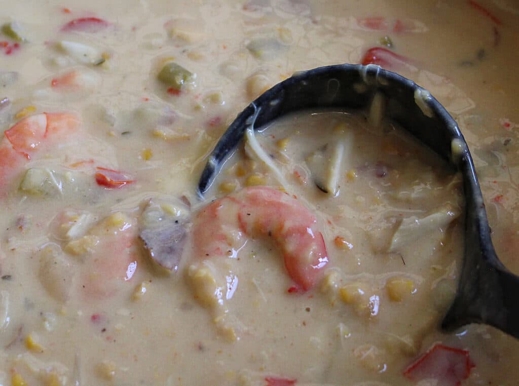 Seafood Chowder being stirred on the stove with a black ladle.