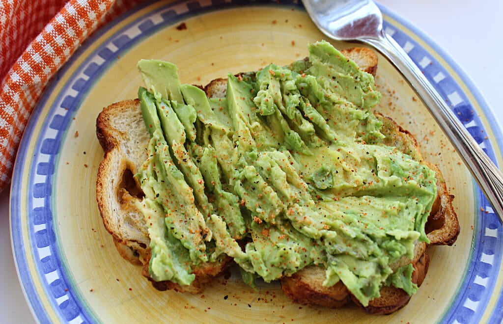close up of prepared avocado toast on a yellow and blue plate