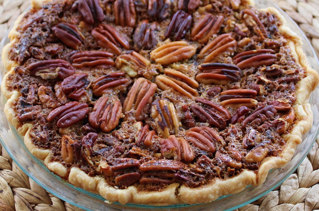 Baked pecan pie in a glass pie plate on a woven place mat