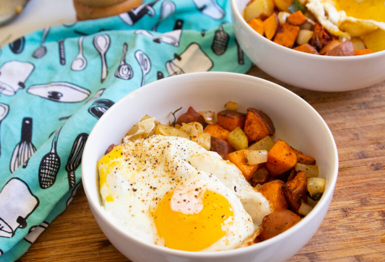 Air fryer sweet potato hash with a fried egg on top in a white bowl.