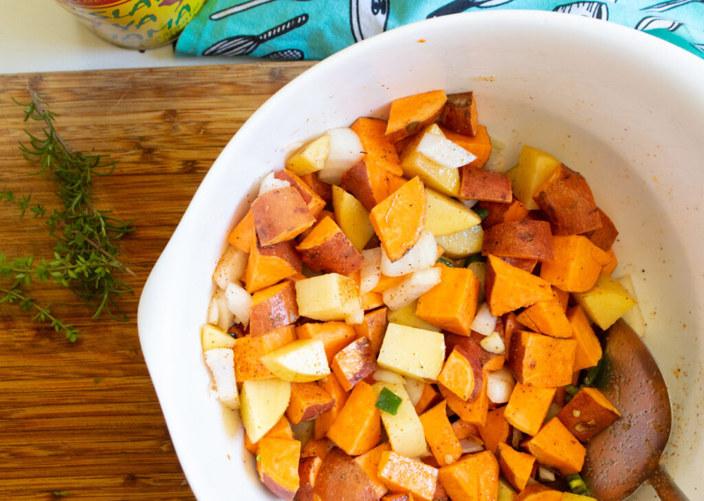 raw sweet potato hash on a butcher block in a white mixing bowl