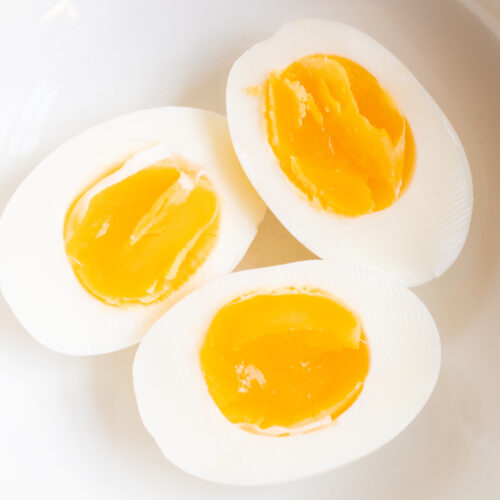 close up of 3 perfect soft boiled egg halves in a white bowl