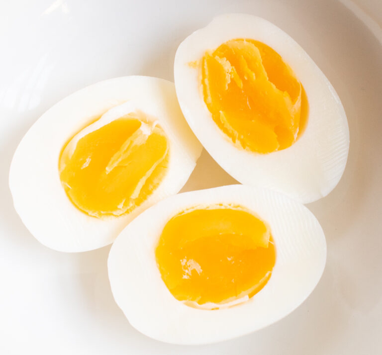 close up of 3 perfect soft boiled egg halves in a white bowl