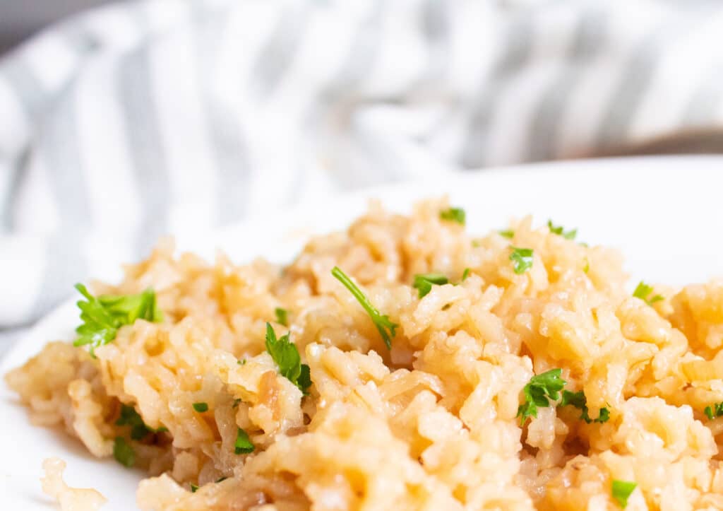 Easy Baked Rice Recipe with fresh parsley on a white plate