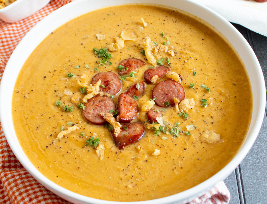 sweet and savory roasted butternut squash soup with sausage in a white bowl