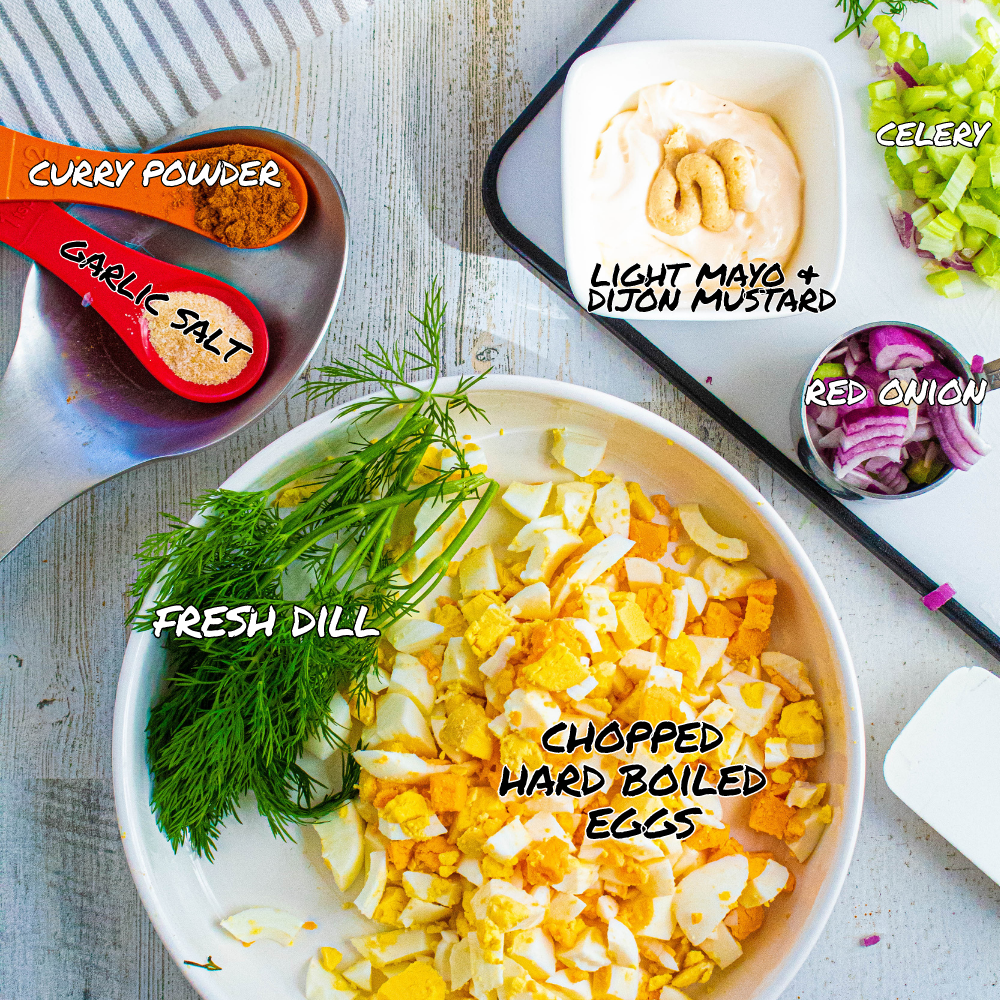 the best egg salad recipe ingredients with labels on a wood table and a white cutting board