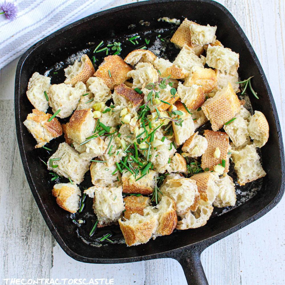 close up of unbaked croutons with fresh herbs in a cast iron skillet
