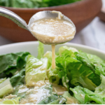 close up caesar salad dressing drizzles on the salad.
