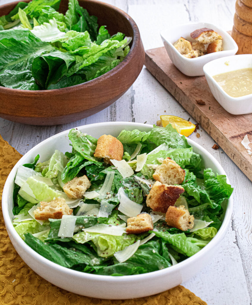 Classic Caesar Salad dressing served with romaine lettuce, homemade croutons in a wooden bowl