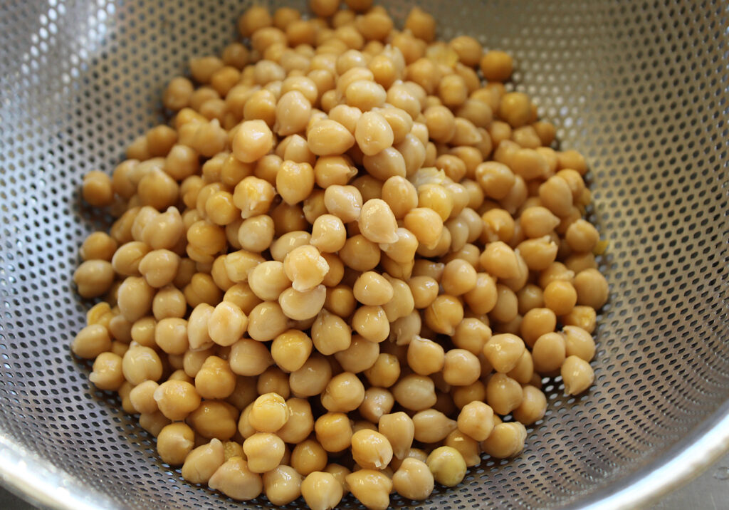 Close up of canned chickpeas draining in a metal colander.