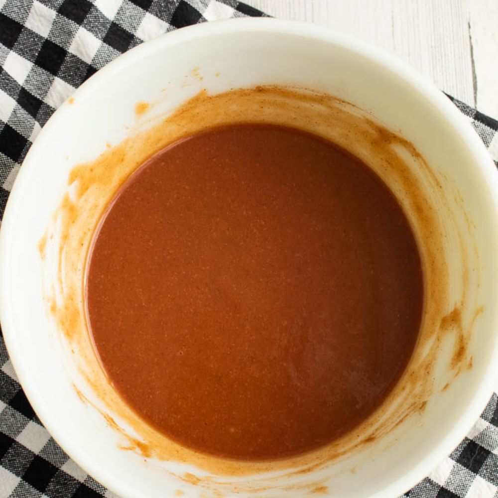 Semi-homemade BBQ sauce in a white bowl set on a black and white checkered towel.
