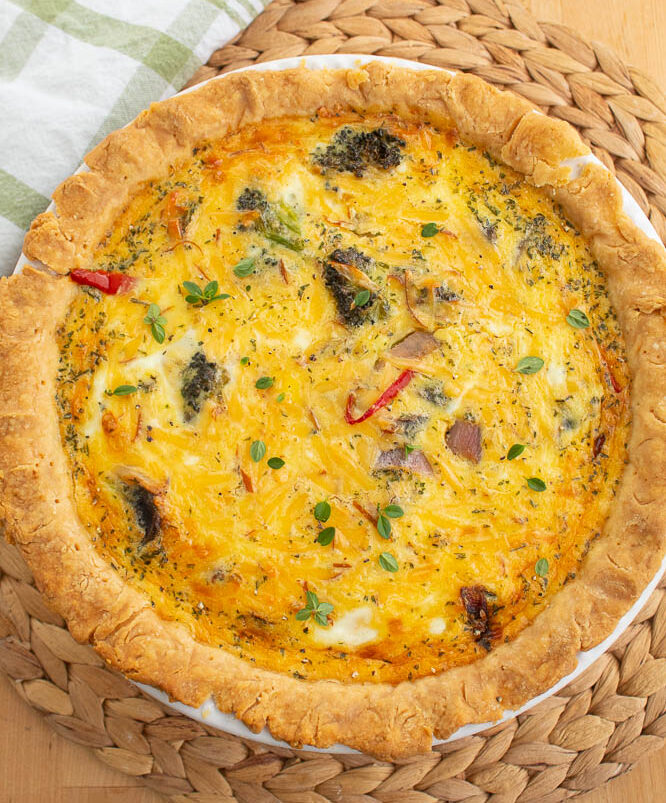 Roasted Vegetable Quiche with smoked gouda Cheese on a bamboo mat.